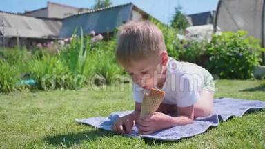 一个小男孩躺在草坪上，高兴地吃冰淇淋。 <strong>炎炎夏日</strong>，冷甜甜点